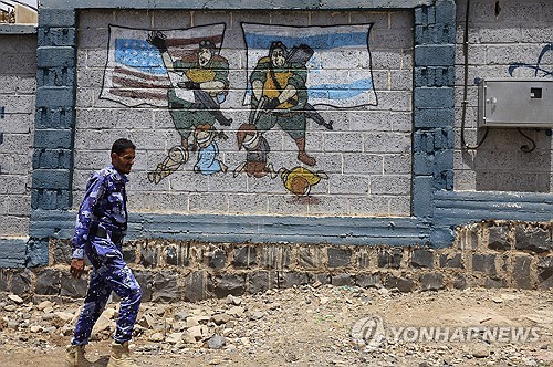 예멘 사나에서 한 후티 반군 대원이 팔레스타인 지지 낙서가 그려진 벽 옆을 지나가고 있다.