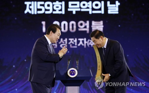 (서울=연합뉴스) 서명곤 기자 =  윤석열 대통령이 5일 서울 삼성동 코엑스에서 열린 제59회 무역의날 기념식에서 한종희 삼성전자 대표이사에게 1천200억불 수출의 탑을 수여하고 있다. 2022.12.5[대통령실통신사진기자단] seephoto@yna.co.kr