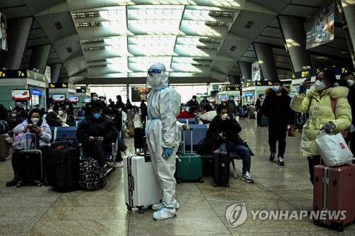 (베이징 AFP=연합뉴스) 28일 중국 베이징 기차역에 한 승객이 방역복을 갖춰 입고 서 있다. 2022.12.29 clynnkim@yna.co.kr